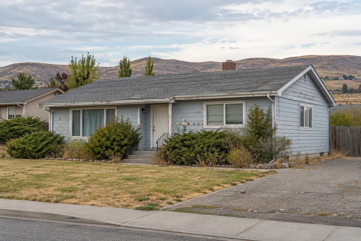 A house with peeling paint and worn roof shingles that needs repairs
